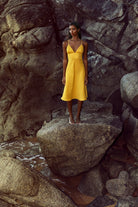 Mustard linen strap dress with a fitted waist and flared skirt.