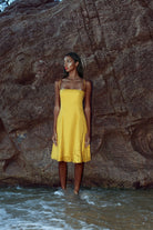 Mustard yellow linen bardot dress with off-shoulder neckline and flared skirt.