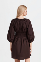 Lia Ruched Minidress in brown with a flattering V-neckline and decorative ties.