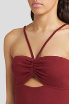 Fitted burgundy dress with lingerie-inspired straps and cutout.